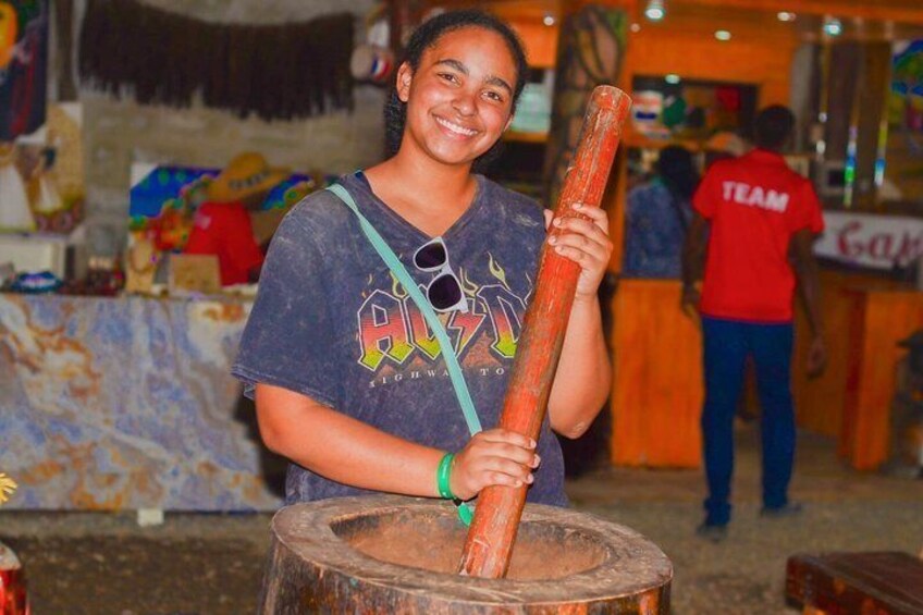 A person holding a large wooden log, standing in front of a rustic barrel. 5