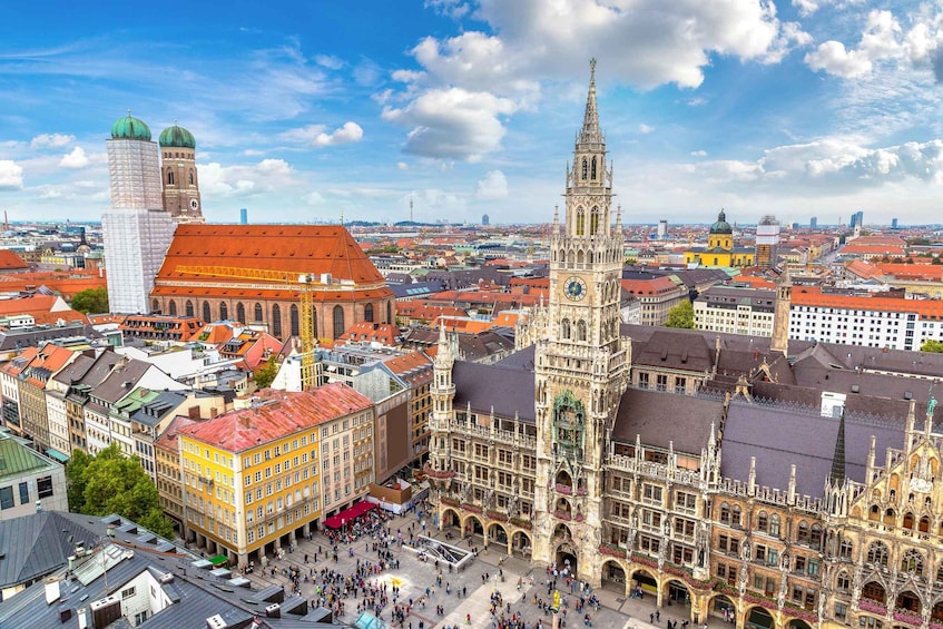A historic cityscape with prominent architecture, including a clock tower and a tall church spire. 1