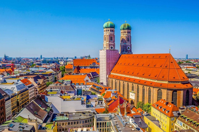 A cityscape with a prominent church featuring a large dome and two towers, surrounded by colorful buildings and a clear blue sky. 5