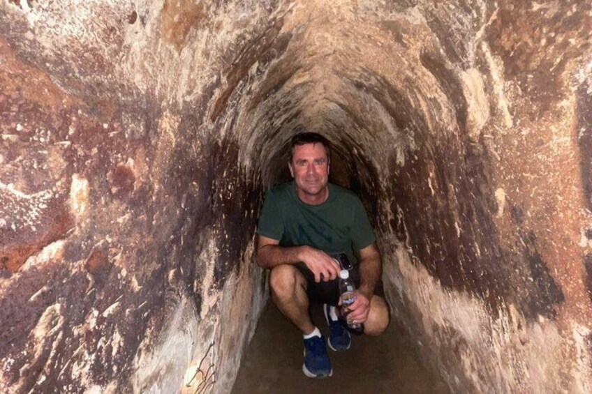 A person sitting in a narrow, rocky tunnel. 4