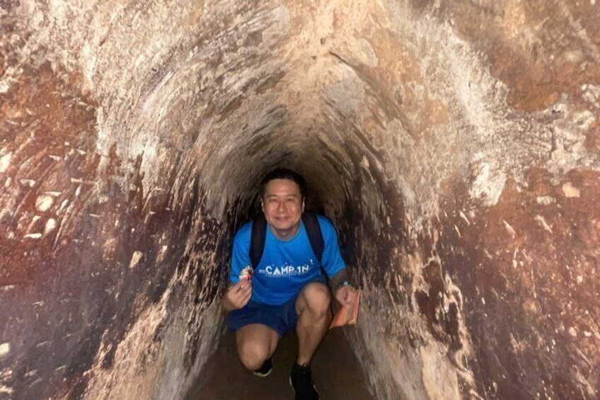 A person sitting inside a narrow, rocky tunnel. 3