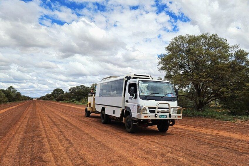A white truck on a dirt road with a clear sky and sparse vegetation. 3