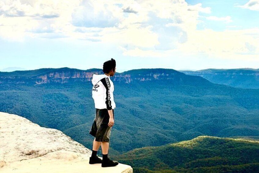 A person standing on a cliff overlooking a mountainous landscape. 5