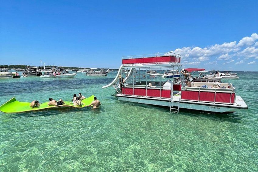 A clear blue sea with boats, including a red and white boat with people on it. 2