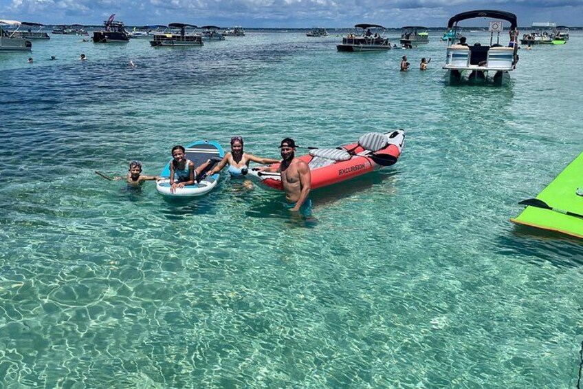 People in inflatable boats on clear turquoise water, surrounded by other boats and a distant island. 4