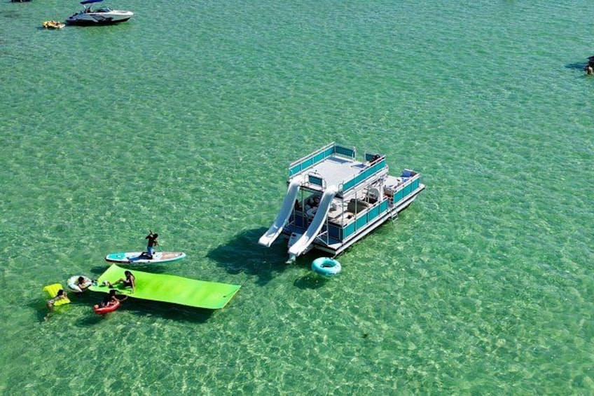 A boat with a green platform and people on it, floating on clear water. 5