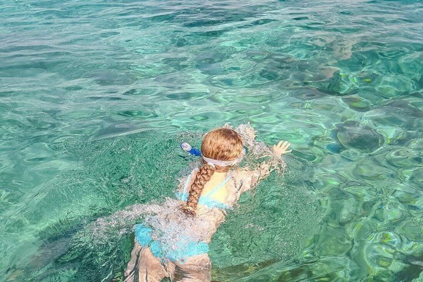 A person swimming in clear blue water. 3
