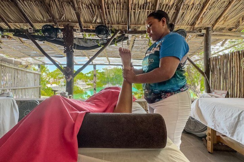 A person receiving a massage on a massage table under a thatched roof. 2