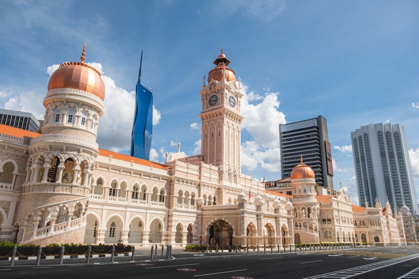 A historic building with domed towers and a clock tower, surrounded by modern skyscrapers. 1