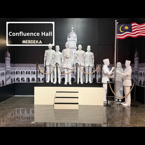 A Confluence Hall exhibit with a Malaysian flag, a clock tower, and a group of figures in traditional attire. 4
