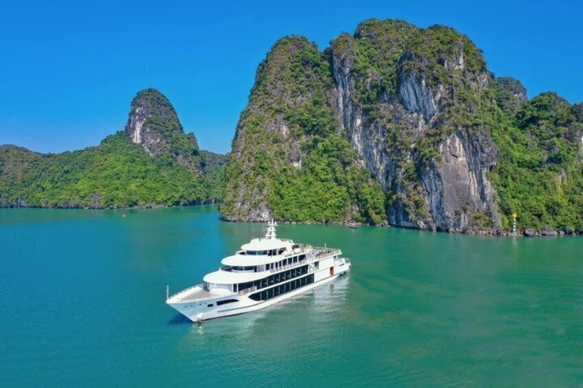 A white boat on turquoise water with green cliffs in the background. 1