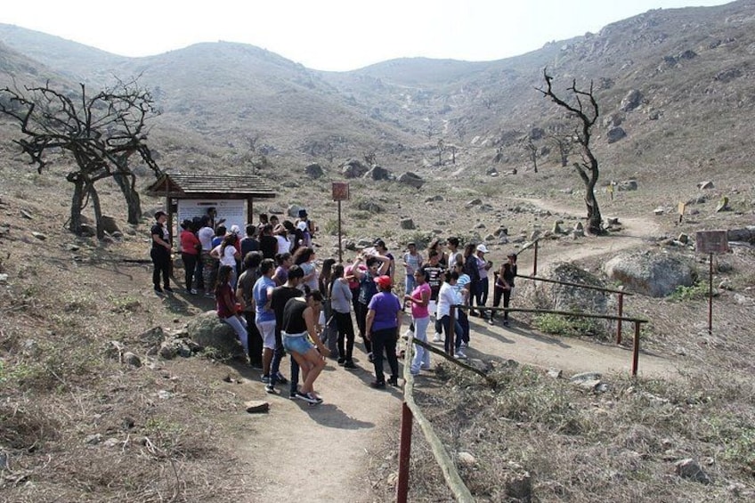 A group of people standing on a dirt path in a mountainous area with rocky terrain and sparse vegetation. 4