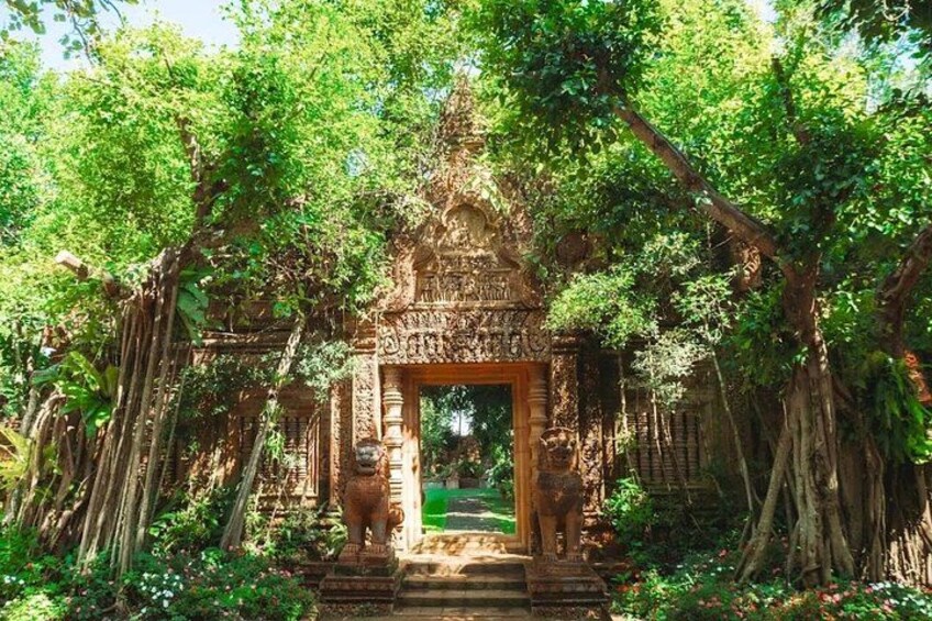 An ancient temple entrance surrounded by lush greenery and large trees. 5