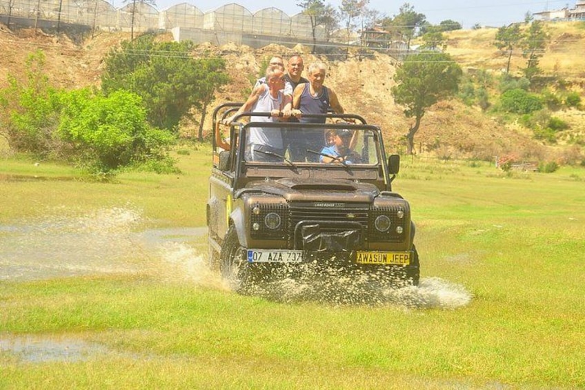 A jeep driving through a grassy field with water splashing around. 2