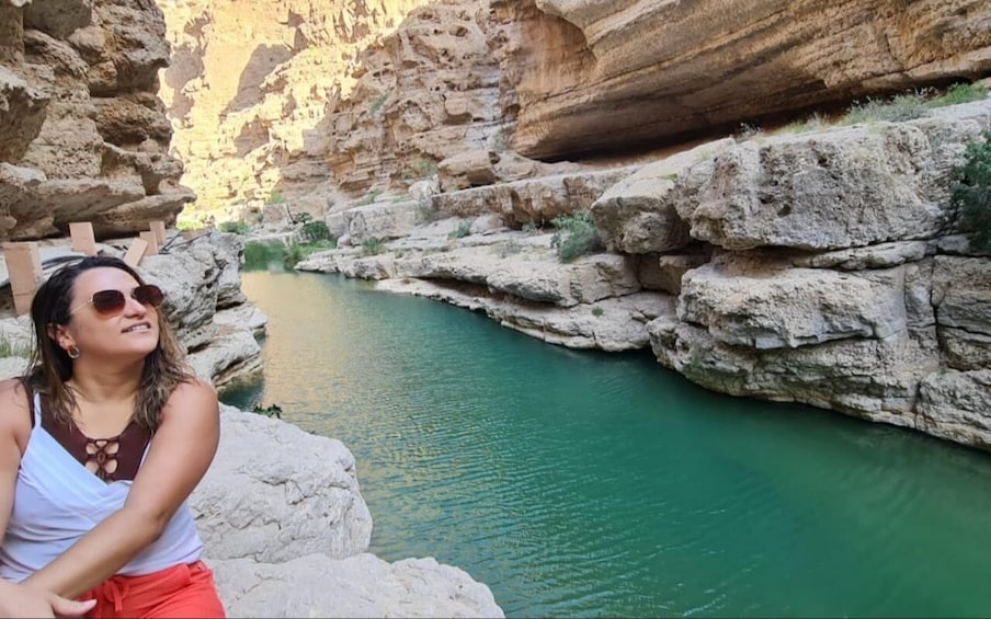 A person sitting by a river in a canyon with rocky cliffs. 1