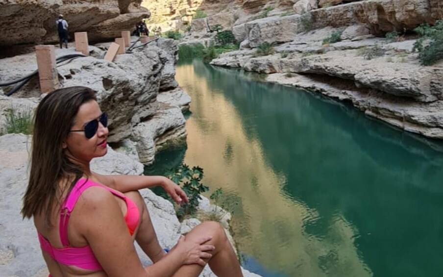 A person sitting by a calm river in a rocky canyon. 4