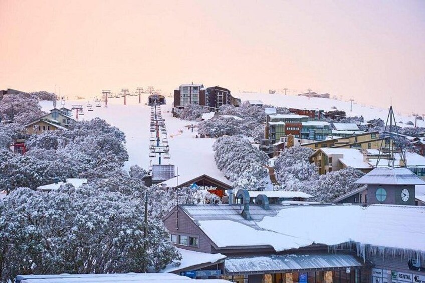 A snowy town with buildings, a clock tower, and a ski lift in the background. 4