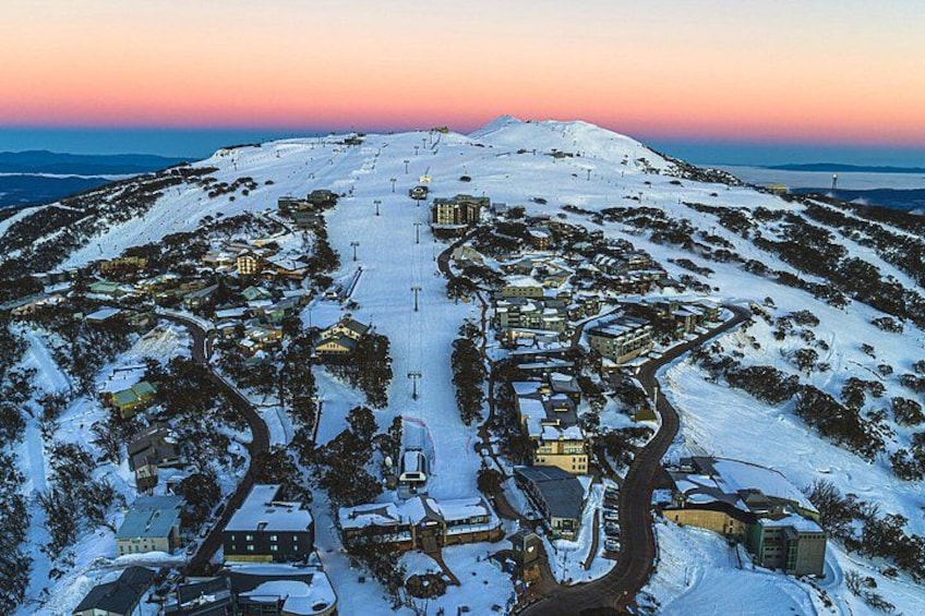 A snow-covered ski resort with a ski lift, buildings, and a mountain backdrop. 3