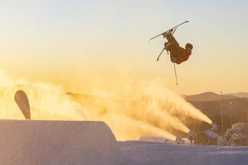 A skier performing a jump in a snowy landscape with a ski lift in the background. 2