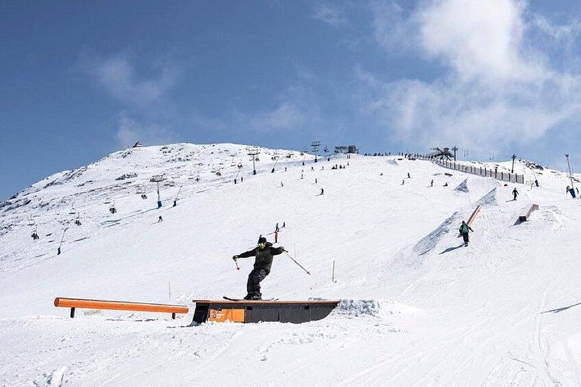 A snowy ski slope with a person performing a trick on a rail. 3