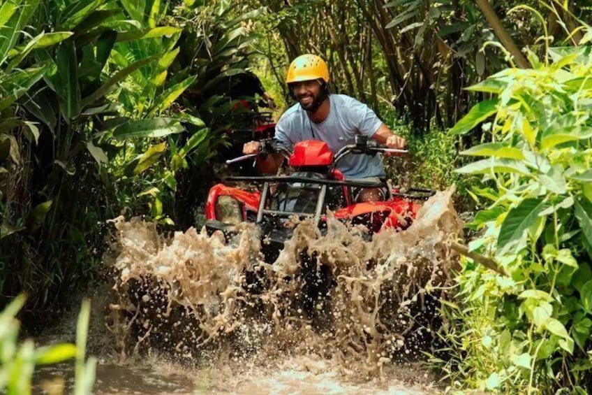A person riding a red ATV through a muddy water crossing. 1