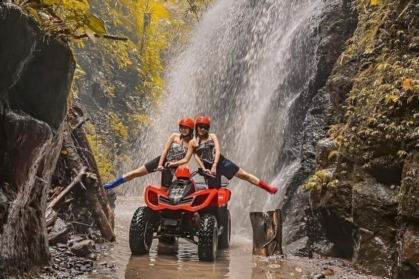 An ATV navigating a narrow water crossing with a waterfall in the background. 2