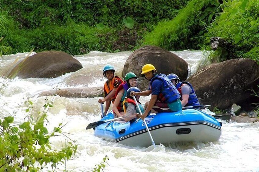 A group of people rafting on a river with rocks and greenery around. 5
