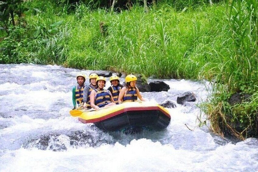 A group of people in a raft navigating a river surrounded by greenery. 4