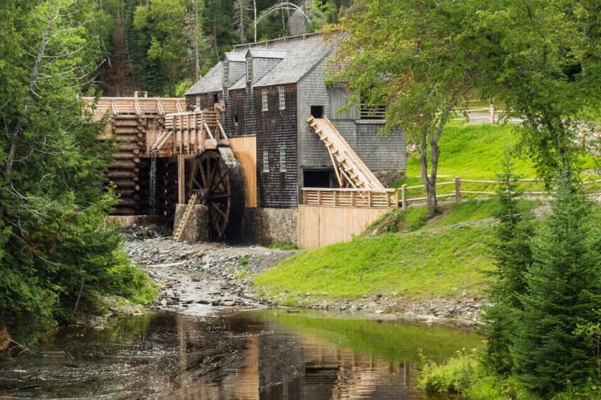 A wooden mill with a water wheel, surrounded by trees and a small stream. 3
