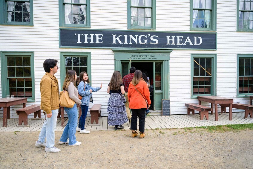 A group of people standing in front of a building with a sign that reads 'THE KING'S HEAD.' 2