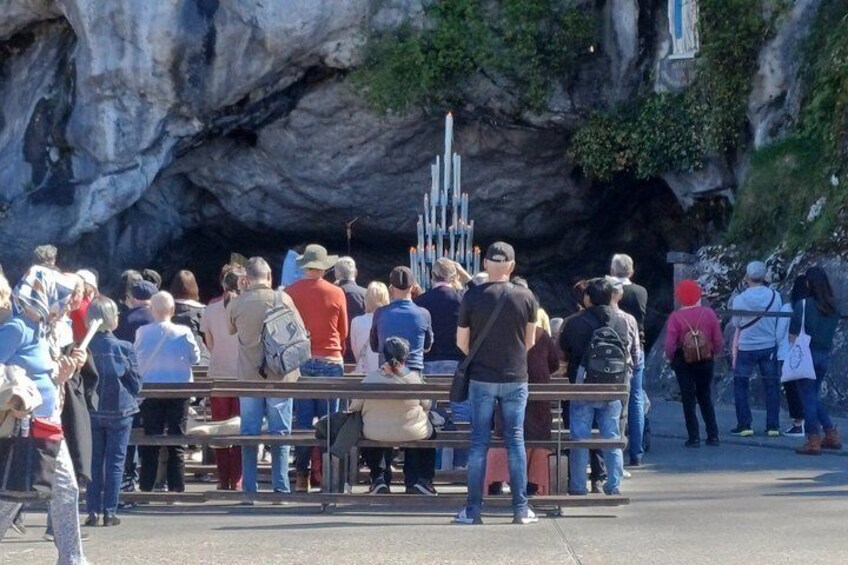 A crowd of people standing in front of a cave entrance with a vertical structure inside. 3
