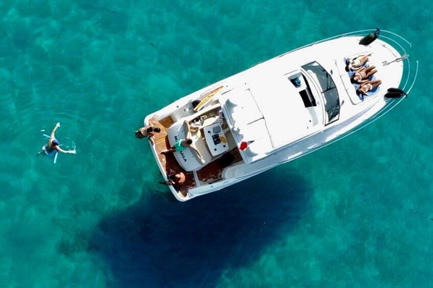 A white boat with people on board, floating on clear turquoise water. 3