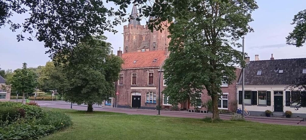 A historic building with a red-tiled roof, surrounded by trees and a well-maintained lawn. 3