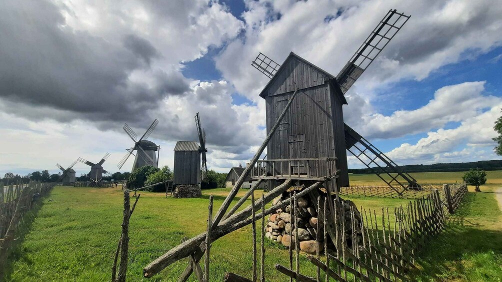 A rural landscape with multiple traditional windmills and a wooden structure with a ladder. 1
