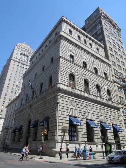 A historic building with large windows and a stone facade, surrounded by modern high-rise buildings. 5