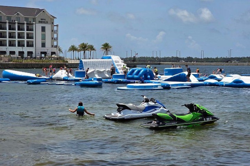 A water park with inflatable water slides and jet skis on the water. 1