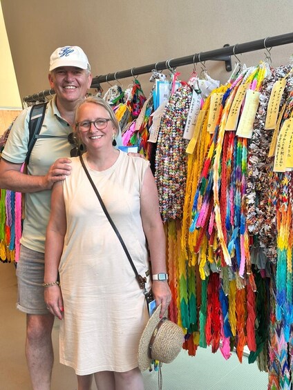 Two people standing in front of a rack of colorful fabric. 2