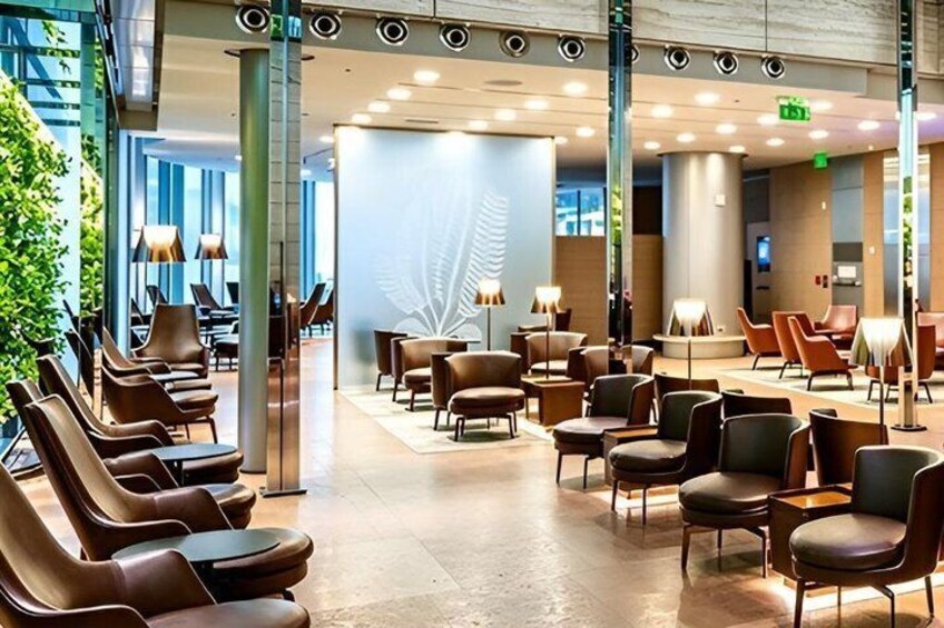 A modern indoor seating area with multiple chairs and tables, a large wall with a leaf design, and a glass wall on one side. 5