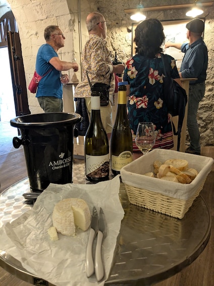 A table with a cheese, wine bottles, a basket of bread, and a coffee maker. 5