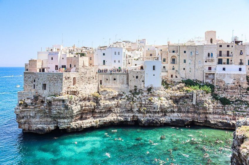 Un pueblo costero construido sobre un acantilado rocoso, con aguas azules cristalinas abajo. 5