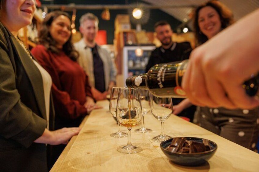 A person pouring a drink into a glass at a bar. 4
