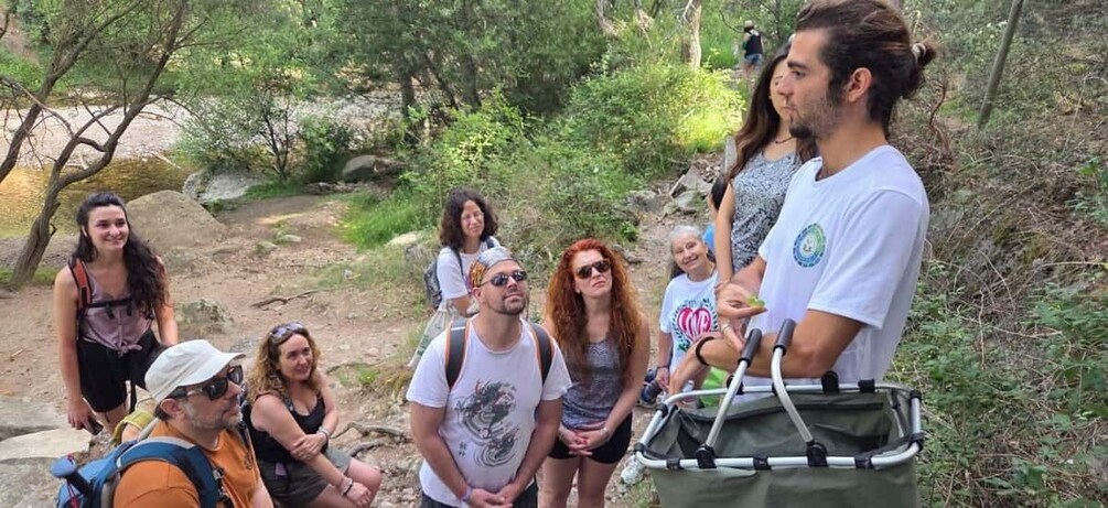 A group of people hiking in a wooded area with a backpack and a green bag. 1