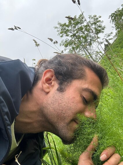 A person in a natural setting with green foliage and tall grasses. 4
