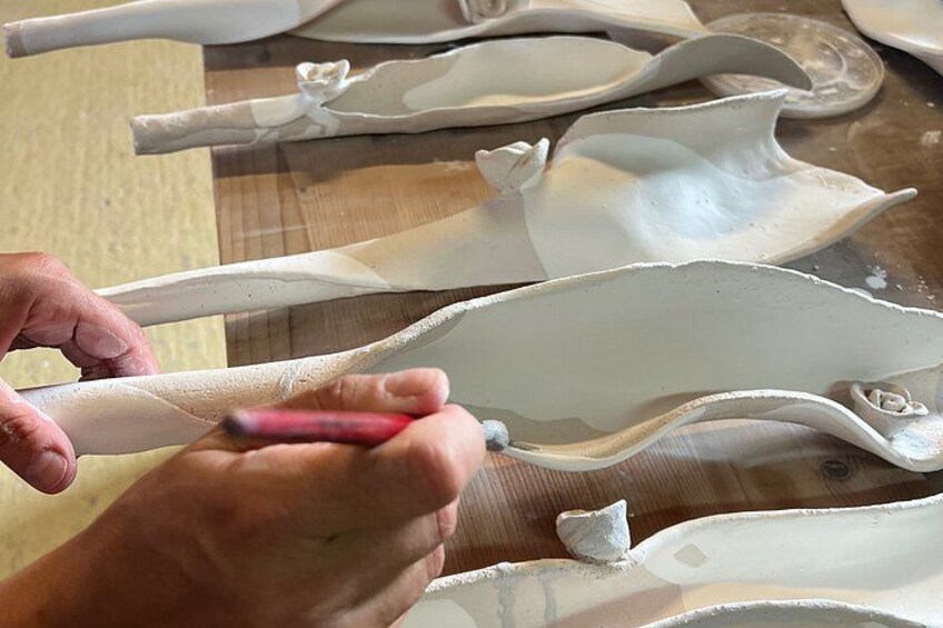 Hands shaping a clay object on a table. 2