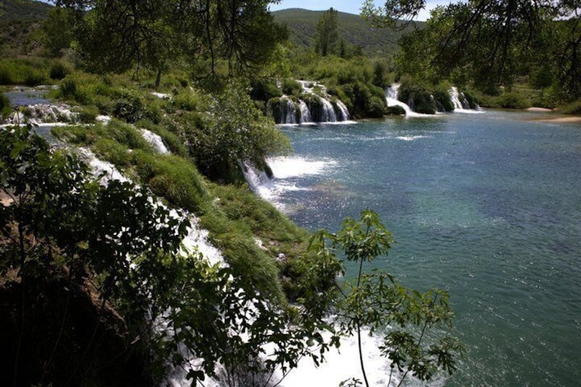 A river with multiple waterfalls surrounded by lush greenery. 4