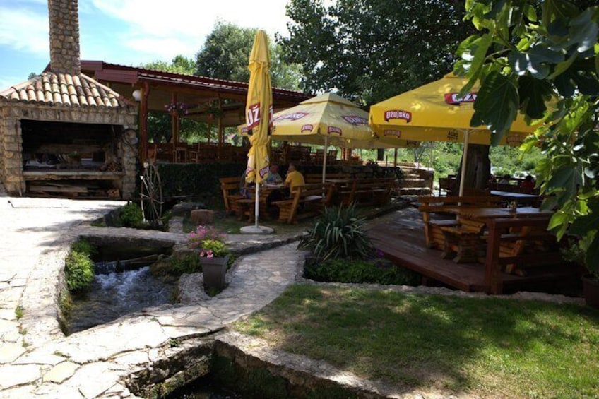 An outdoor restaurant with stone flooring, yellow umbrellas, and a brick oven. 5