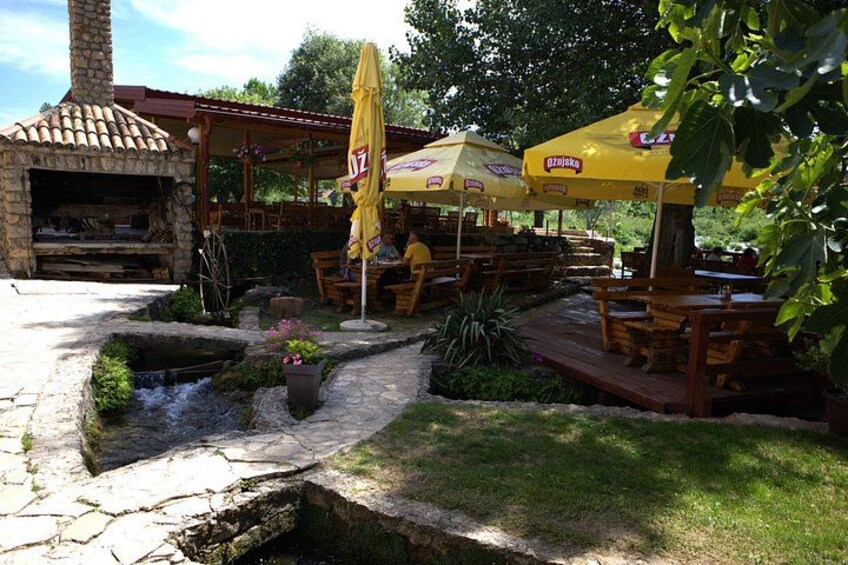 A rustic outdoor dining area with stone tables and yellow umbrellas. 5