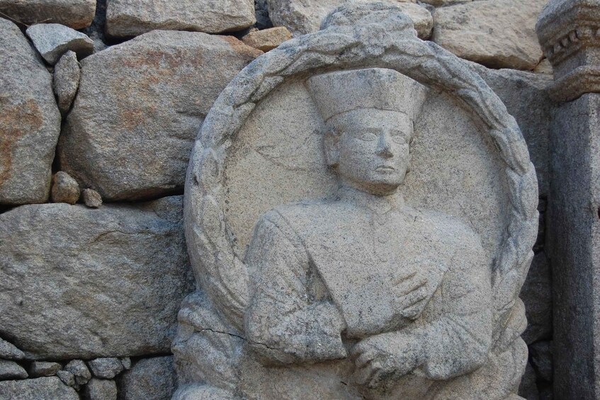 A stone Buddha statue with a halo, set against a stone wall. 2