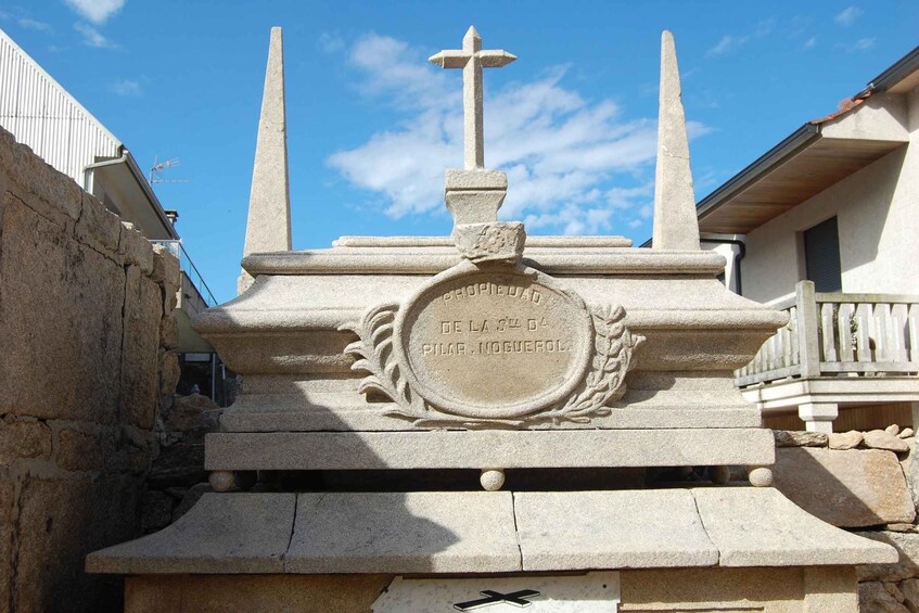 A stone monument with a cross and inscriptions, set against a clear sky. 3