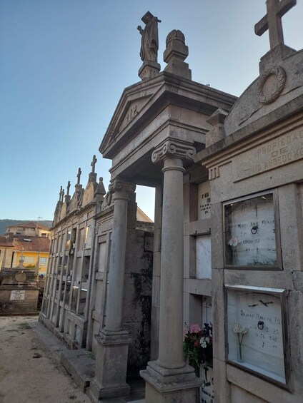 A cemetery with stone crosses and tombstones, some with flowers. 1